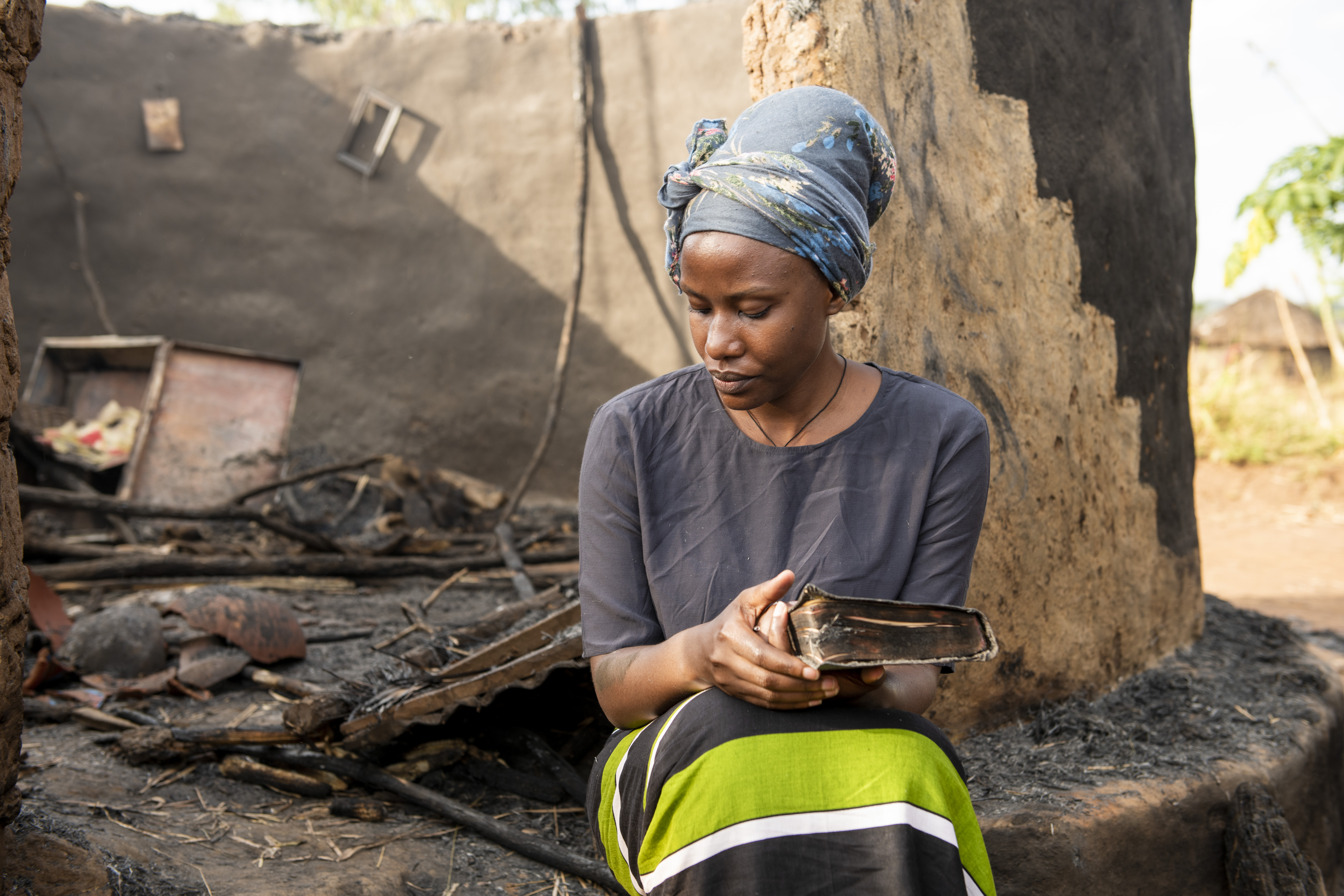 How We Love Our Enemies Woman sitting by her burned home. President's Letter Story.