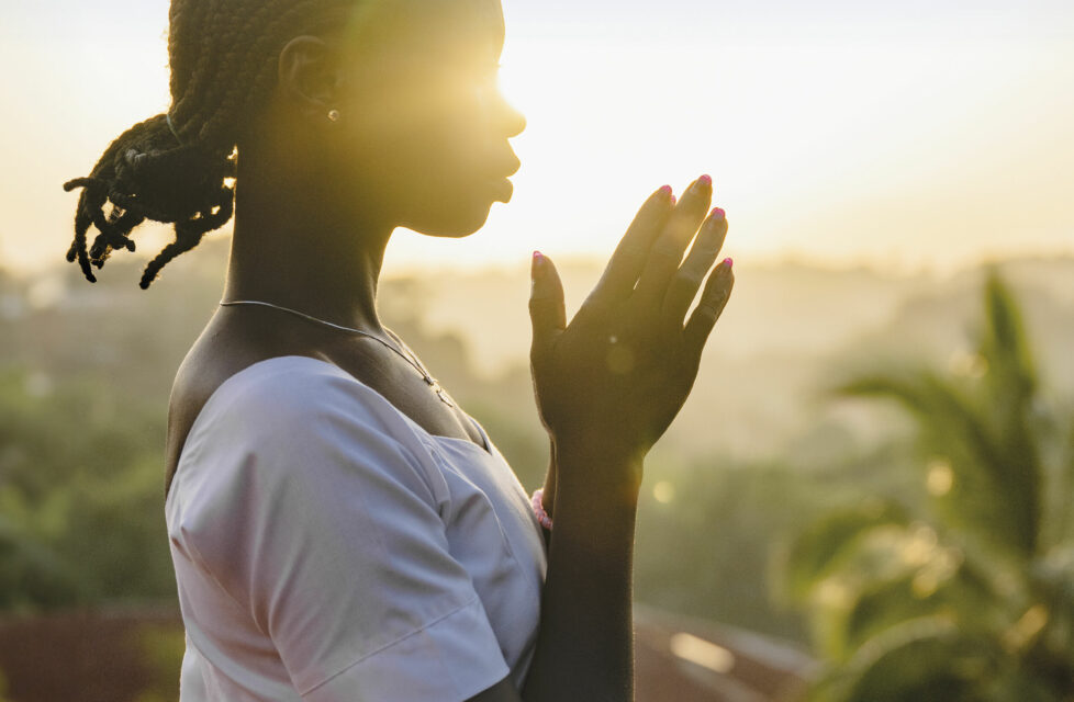 The Shocking Wickedness of Lost Men Woman praying with sunset behind her