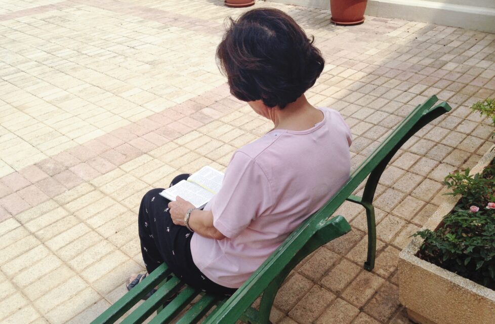 Syrian Christians Remain Faithful After Islamist Attacks a woman sits on a bench outside reading her bible